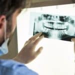 male dentist examines dental x-ray