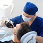 Patient receiving dental bridge treatment under bright overhead light